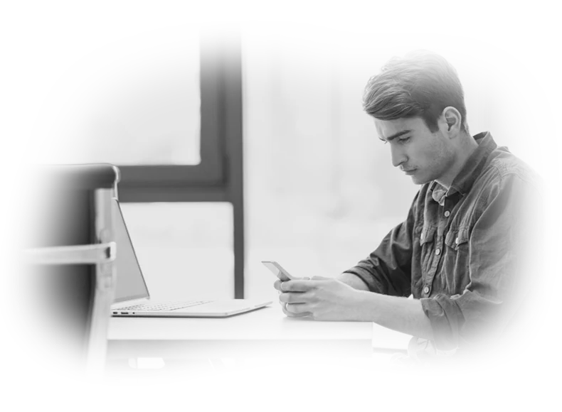 Monochrome photography of a focused developer testing web on a smartphone, representing administrative back-end management across alternative CMS platforms.